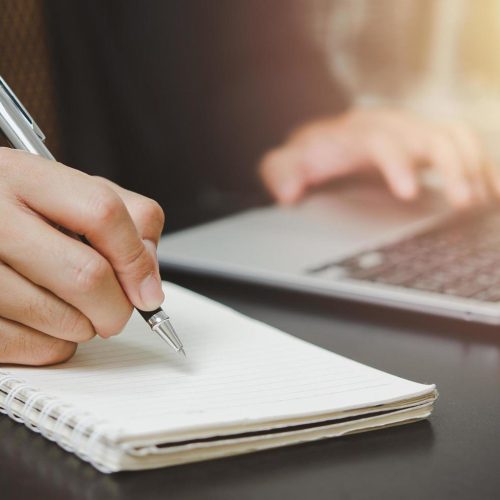 person-man-holding-pen-write-plan-or-idea-on-book-with-computer-laptop-on-desk-free-photo